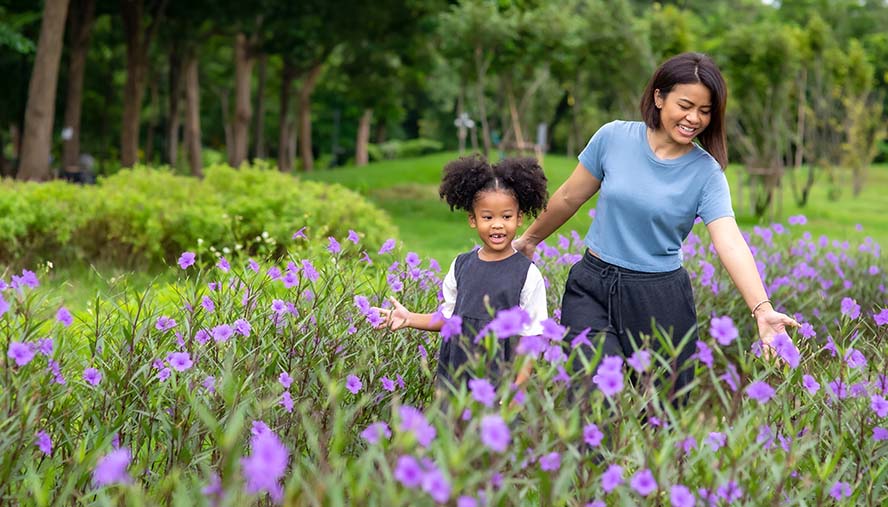 woman and child walking in field of flowers and grasses