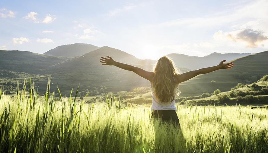 Woman standing in field watching sunrise